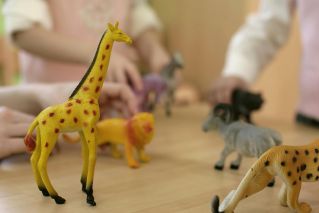 Close-up of children's hands playing with animal plastic toys.